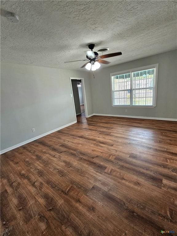 unfurnished room featuring a ceiling fan, baseboards, a textured ceiling, and dark wood-type flooring