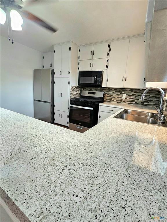 kitchen with decorative backsplash, ceiling fan, appliances with stainless steel finishes, a sink, and white cabinets
