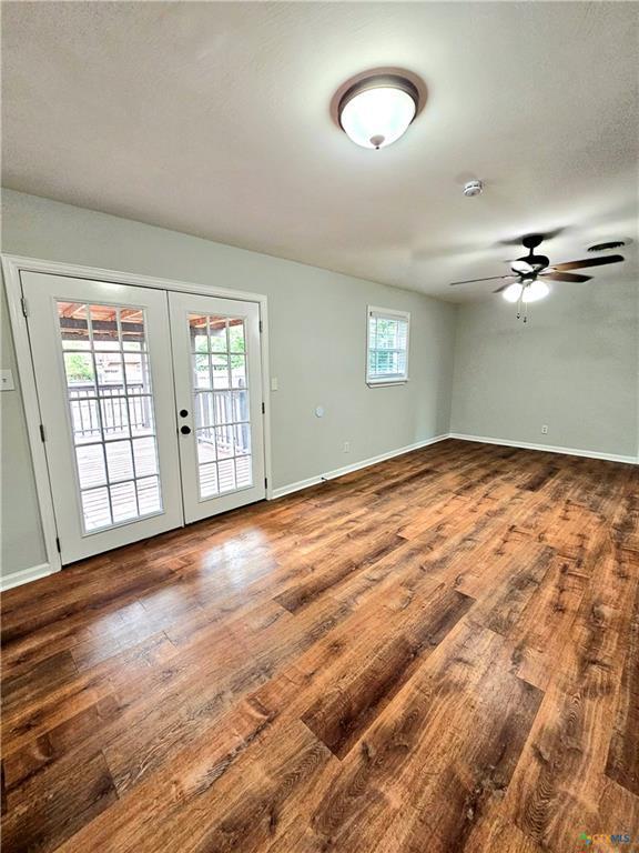 spare room with french doors, baseboards, ceiling fan, and wood finished floors