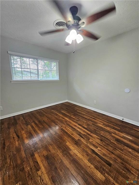 spare room featuring a ceiling fan, baseboards, and dark wood-type flooring