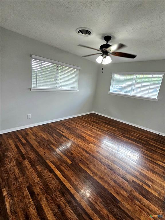 unfurnished room featuring visible vents, a textured ceiling, and wood finished floors