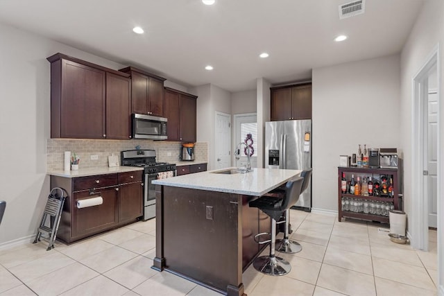 kitchen featuring a kitchen bar, appliances with stainless steel finishes, light tile patterned floors, and sink