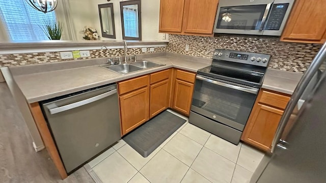 kitchen with backsplash, light tile patterned flooring, sink, and appliances with stainless steel finishes