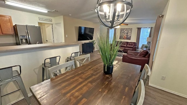 dining area with dark wood-type flooring and an inviting chandelier