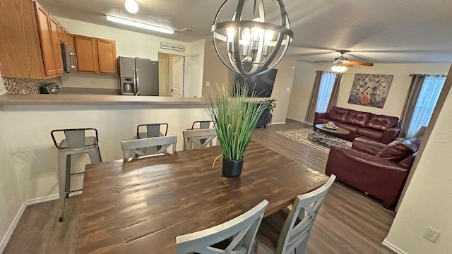 dining area featuring a textured ceiling, ceiling fan with notable chandelier, and dark hardwood / wood-style floors