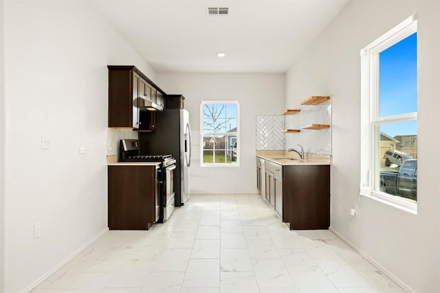 kitchen with sink, stainless steel gas stove, dark brown cabinetry, and backsplash