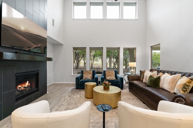 living room featuring a wealth of natural light, light hardwood / wood-style floors, and a high ceiling