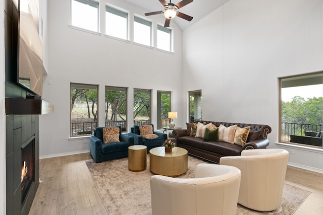 living room with light hardwood / wood-style flooring, a healthy amount of sunlight, and a high ceiling