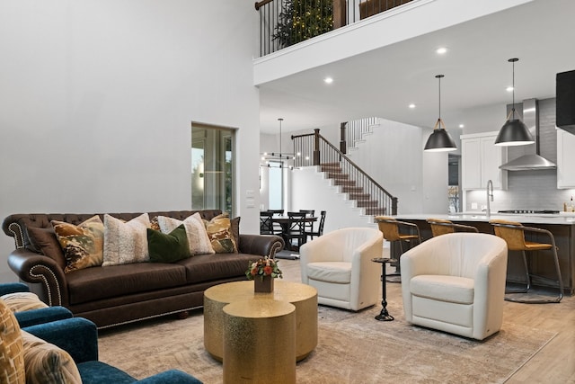 living room with a towering ceiling, an inviting chandelier, and light hardwood / wood-style flooring