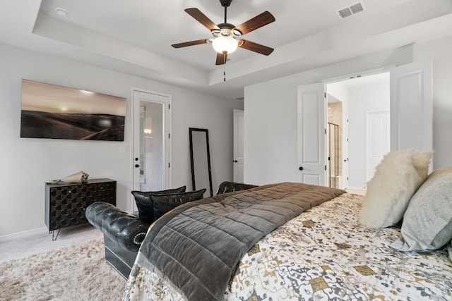 carpeted bedroom with ceiling fan and a tray ceiling