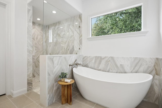 bathroom with tile walls, tile patterned floors, and shower with separate bathtub