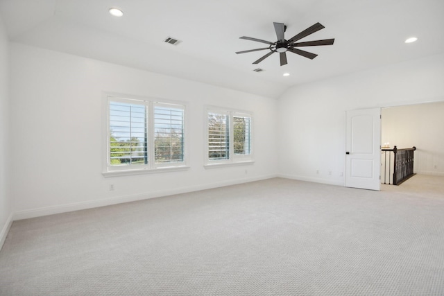 spare room with light carpet, vaulted ceiling, and ceiling fan