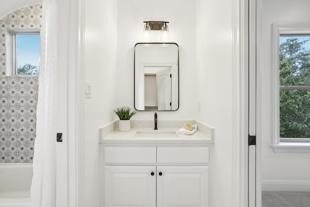 bathroom featuring baseboards, shower / tub combo, and vanity