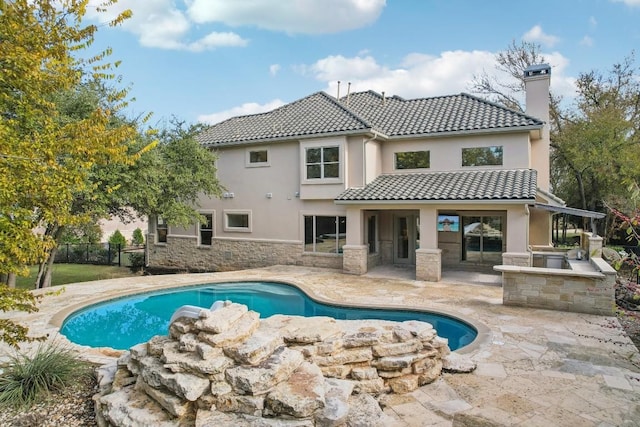 exterior space featuring fence, a tile roof, a chimney, a patio area, and area for grilling