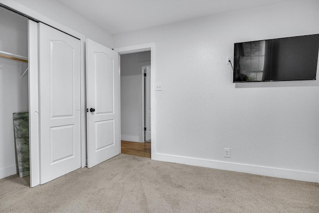 unfurnished bedroom featuring light carpet and a closet