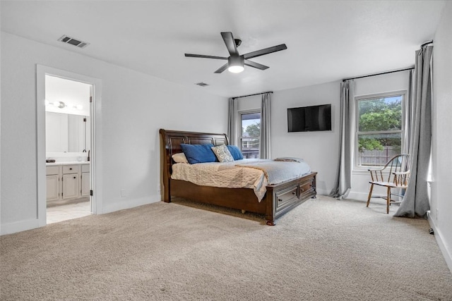 bedroom with ceiling fan, ensuite bathroom, and light carpet