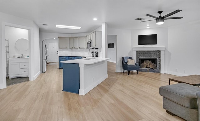 kitchen featuring blue cabinetry, kitchen peninsula, stainless steel appliances, and light hardwood / wood-style flooring