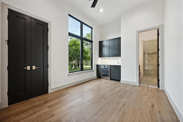 interior space featuring connected bathroom, ceiling fan, beverage cooler, and light hardwood / wood-style floors