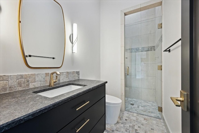 bathroom with vanity, toilet, a shower with shower door, and backsplash