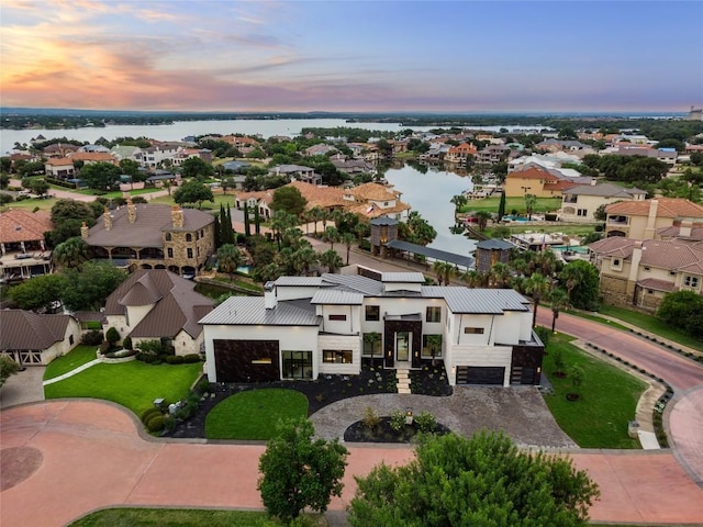 aerial view at dusk featuring a water view