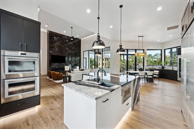 kitchen with pendant lighting, plenty of natural light, light hardwood / wood-style floors, and light stone countertops