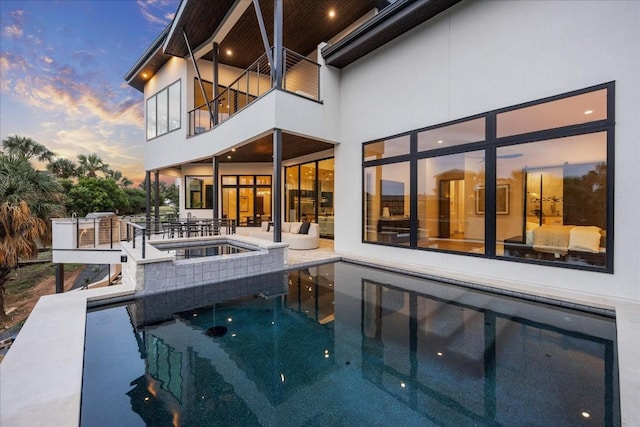 pool at dusk with an in ground hot tub