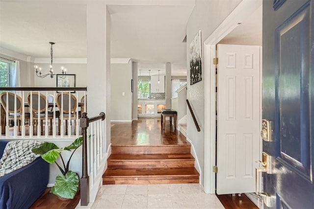 entryway with a chandelier, light hardwood / wood-style floors, and ornamental molding