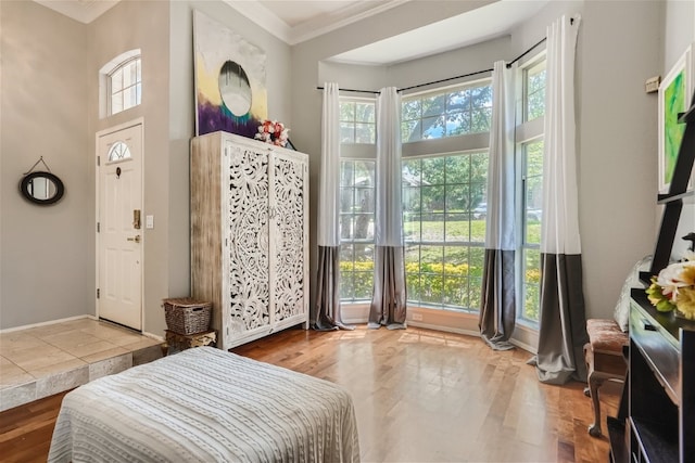 bedroom featuring a towering ceiling, crown molding, baseboards, and wood finished floors