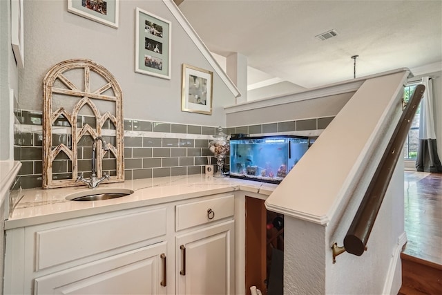 kitchen featuring white cabinetry, sink, light stone countertops, tasteful backsplash, and dark hardwood / wood-style floors