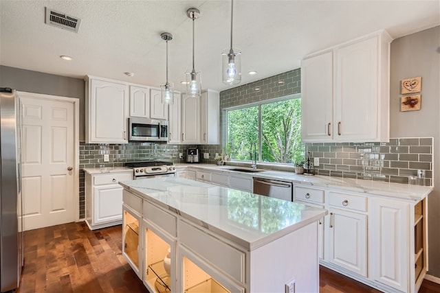 kitchen with white cabinetry, a center island, dark wood-type flooring, hanging light fixtures, and appliances with stainless steel finishes