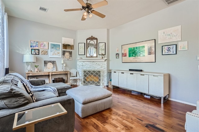 living room featuring wood finished floors, a fireplace, visible vents, and ceiling fan