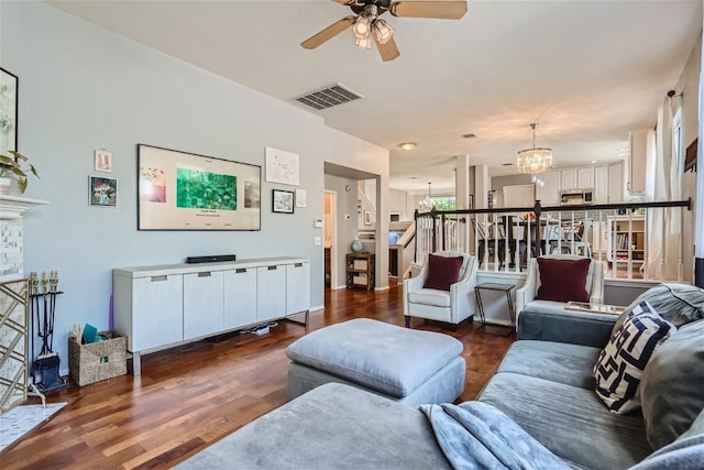 living room with ceiling fan with notable chandelier and dark hardwood / wood-style flooring