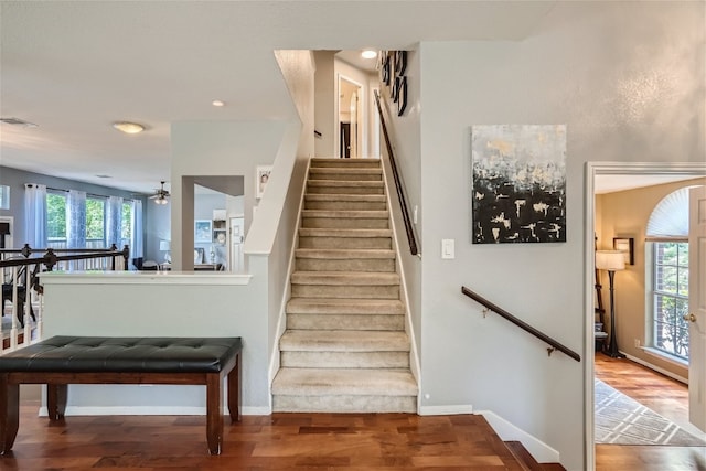 stairs featuring hardwood / wood-style flooring and ceiling fan