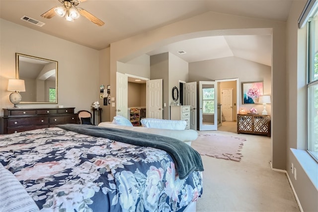 bedroom with connected bathroom, ceiling fan, light colored carpet, and lofted ceiling