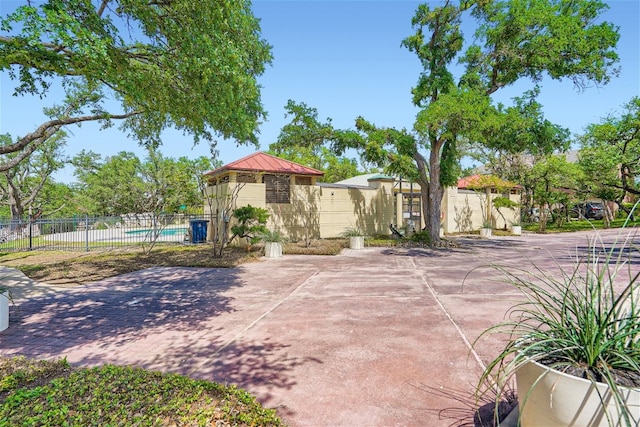 exterior space with a standing seam roof, a community pool, fence, and metal roof