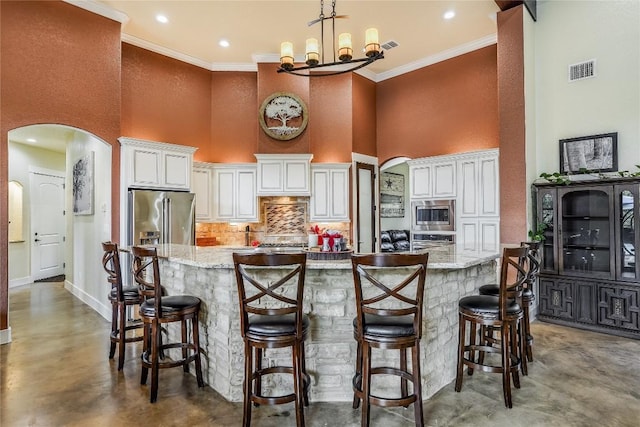 kitchen with light stone countertops, a towering ceiling, ornamental molding, and appliances with stainless steel finishes