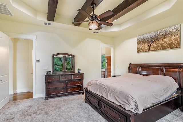 bedroom with a raised ceiling, ceiling fan, beamed ceiling, and light colored carpet