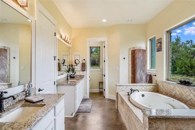 bathroom featuring concrete flooring, vanity, and a relaxing tiled tub