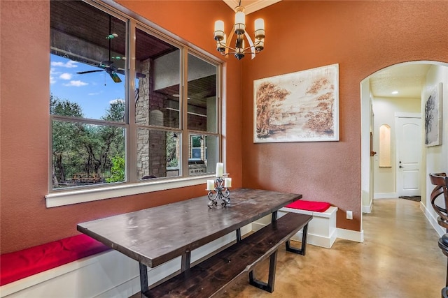 dining space featuring ceiling fan with notable chandelier and concrete flooring