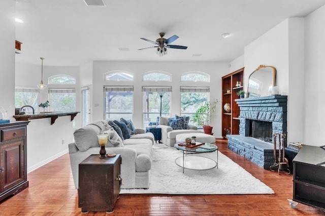 living room with a fireplace, ceiling fan, and light hardwood / wood-style flooring