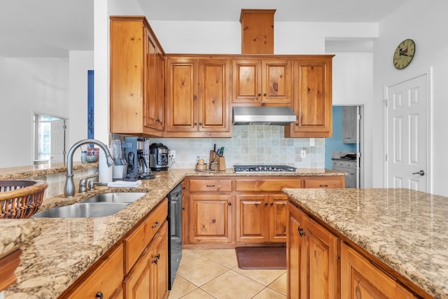 kitchen with sink, tasteful backsplash, light stone counters, stainless steel gas stovetop, and light tile patterned flooring