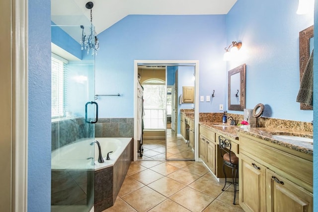 bathroom featuring vanity, vaulted ceiling, an inviting chandelier, tile patterned flooring, and tiled bath