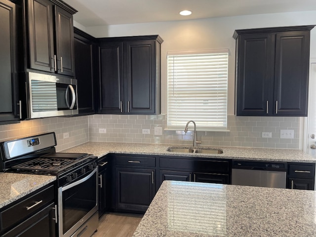 kitchen with appliances with stainless steel finishes, tasteful backsplash, light hardwood / wood-style flooring, and sink