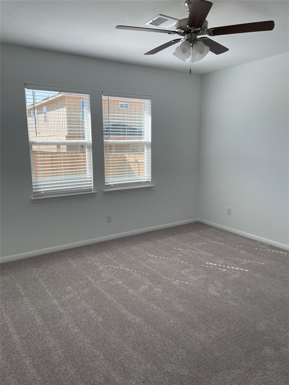 carpeted spare room featuring ceiling fan and a healthy amount of sunlight