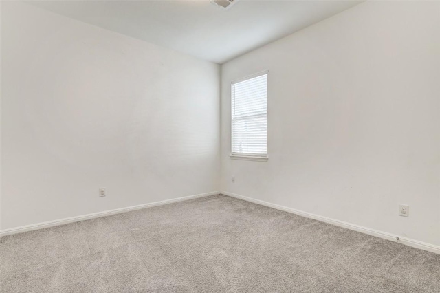 carpeted spare room featuring visible vents and baseboards