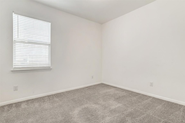 unfurnished room featuring carpet and baseboards