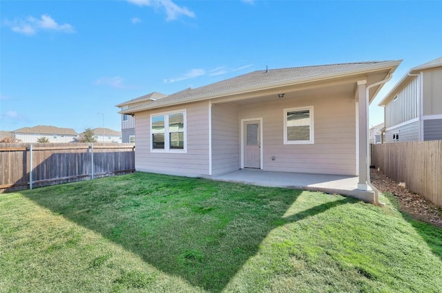 back of property with a patio area, a fenced backyard, and a lawn