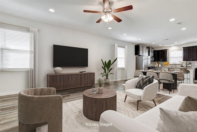 living area featuring light wood-type flooring, baseboards, visible vents, and recessed lighting