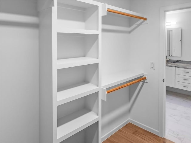 walk in closet with light hardwood / wood-style floors