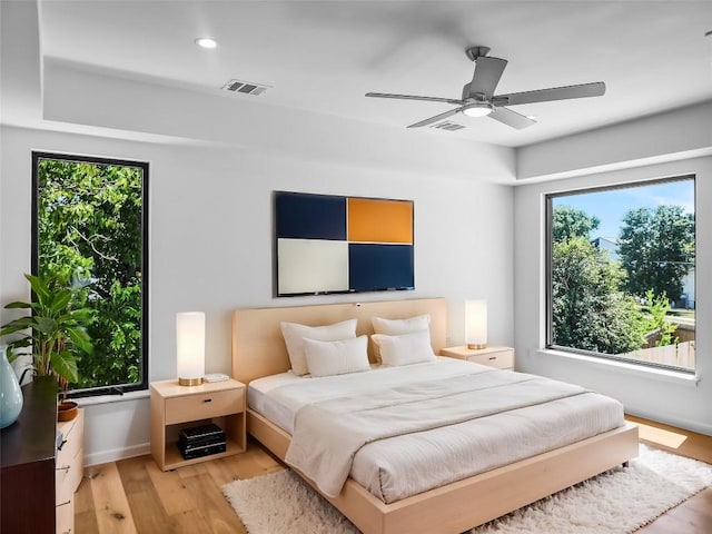 bedroom with multiple windows, ceiling fan, and light wood-type flooring